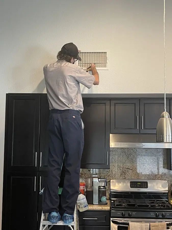 Technician inspecting an air vent during HVAC service in Maumelle